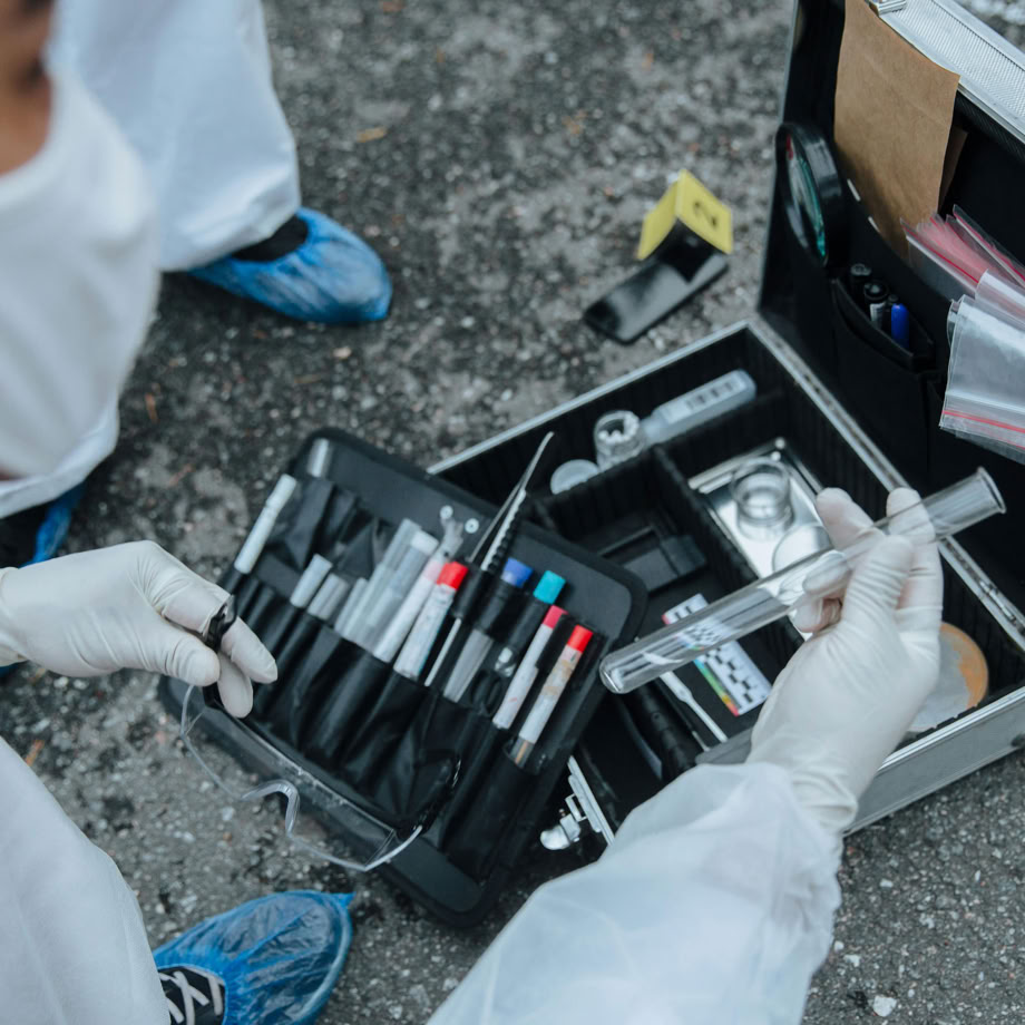 Forensic expert examining evidence with tools at a crime scene investigation outdoors.